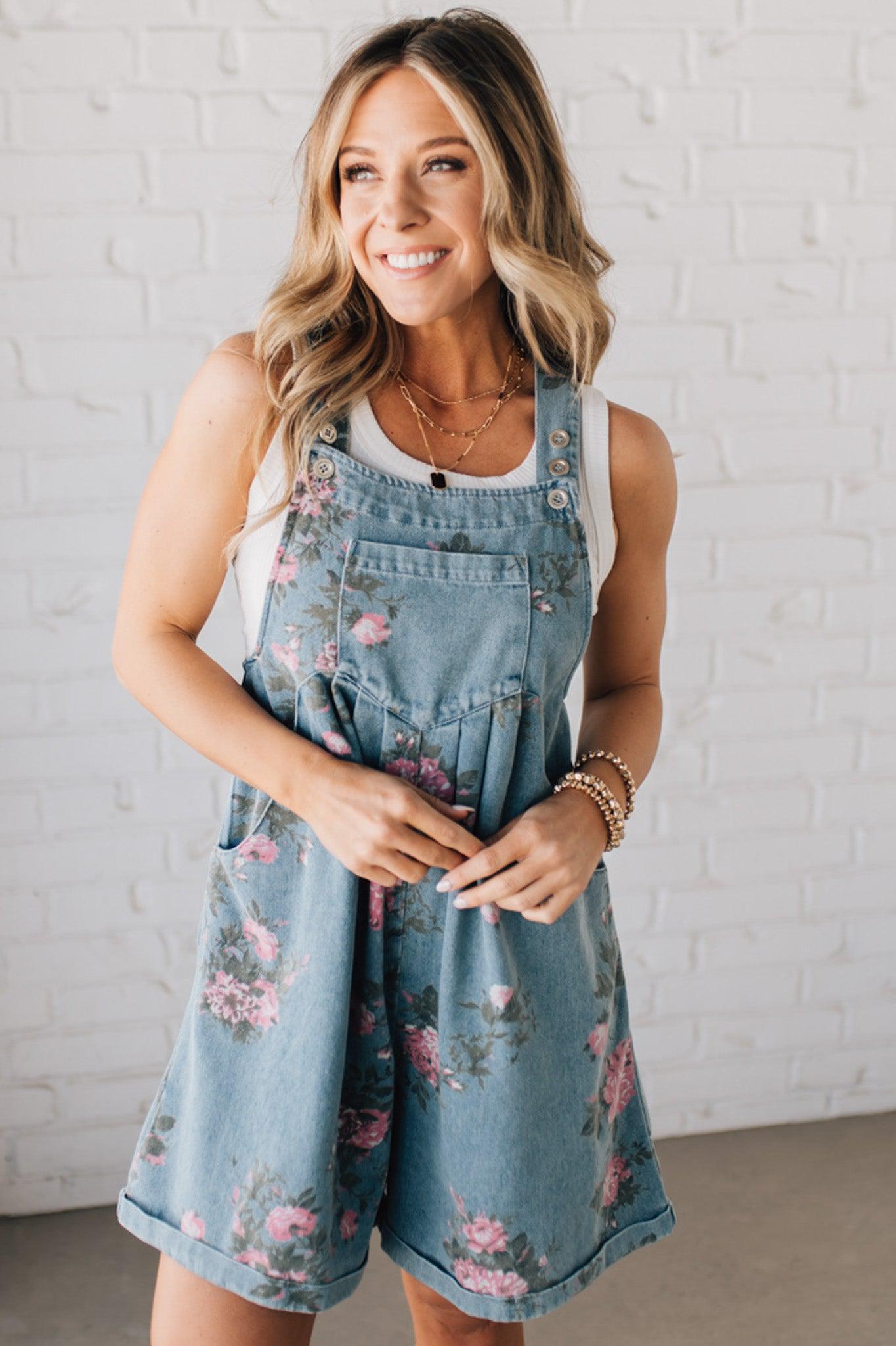 BLONDE WOMAN WEARING FLOWER PRINT WASHED DENIM WIDE LEG SHORTALLS WITH ADJUSTABLE BUTTONED SHOULDER STRAP