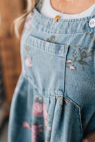 BLONDE WOMAN WEARING FLOWER PRINT WASHED DENIM WIDE LEG SHORTALLS WITH ADJUSTABLE BUTTONED SHOULDER STRAP