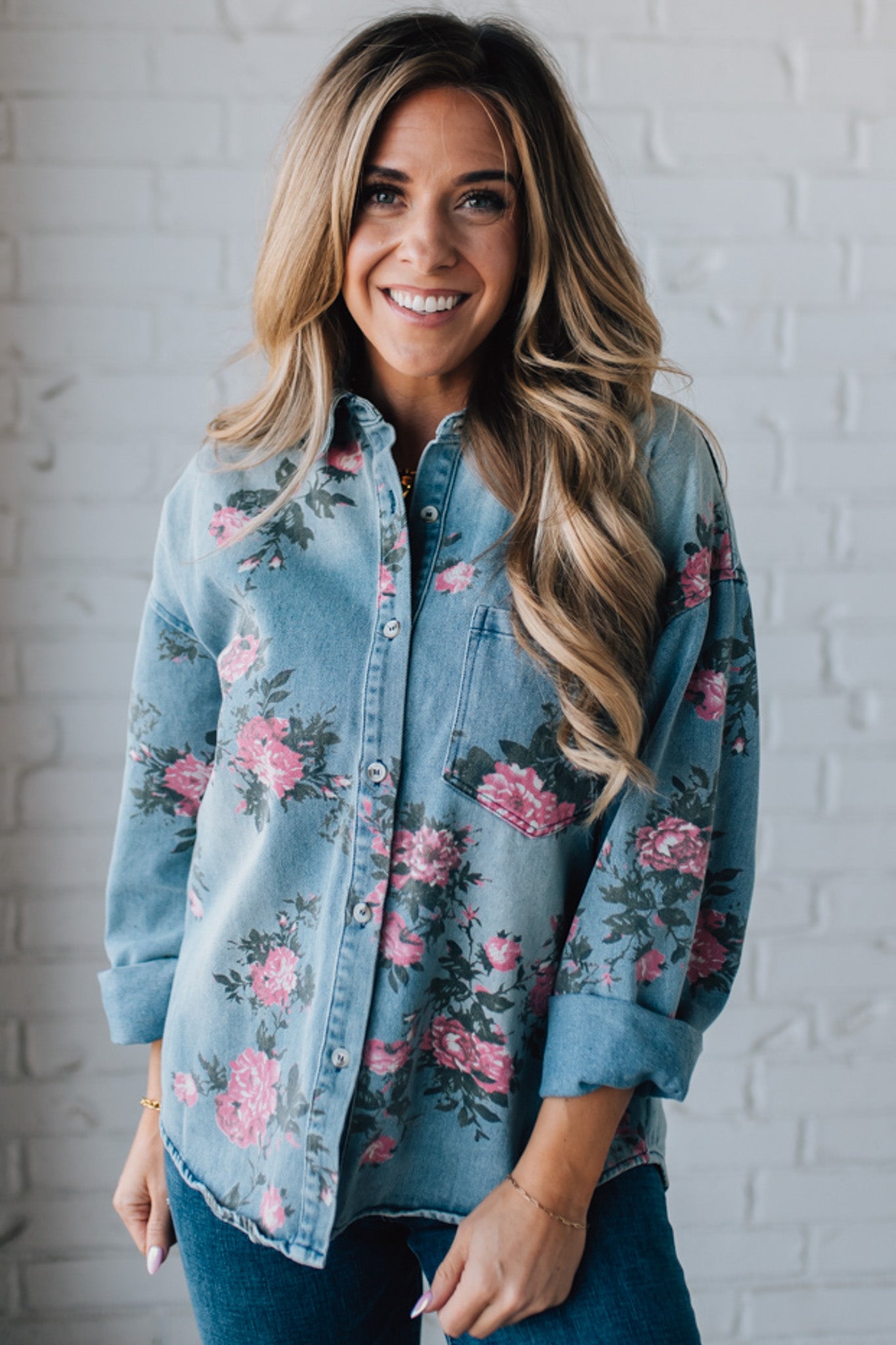 blonde girl modeling a long sleeve button front denim top with pink floral pattern