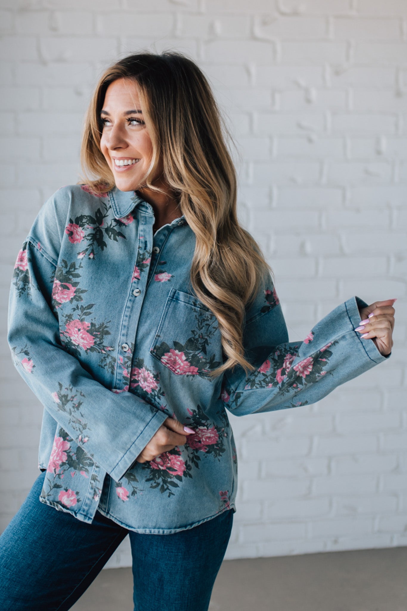 blonde girl modeling a long sleeve button front denim top with pink floral pattern