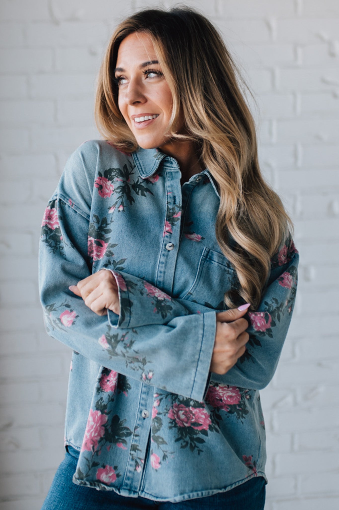 blonde girl modeling a long sleeve button front denim top with pink floral pattern