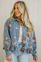 Woman wearing a floral denim jacket with a neutral background