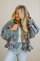 Woman wearing a floral denim jacket with a neutral background