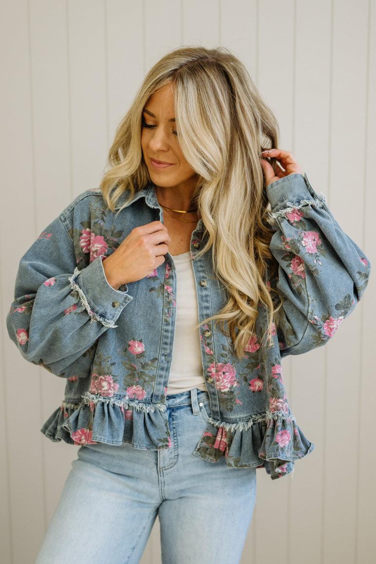 Woman wearing a floral denim jacket with a neutral background