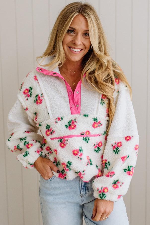 Woman wearing a floral fleece jacket with a pink interior against a neutral background