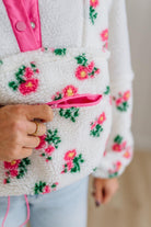 Floral-patterned pouch held by a person wearing a floral jacket.