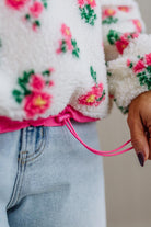 Close-up of a person wearing a floral-patterned cardigan with a blurred background