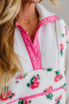 Close-up of a person wearing a white fleece jacket with pink trim and floral patterns.