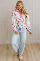 Woman wearing a floral hoodie and light blue jeans indoors.