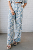 Blonde woman wearing blue and white floral wide leg pants with tie front and side pockets.