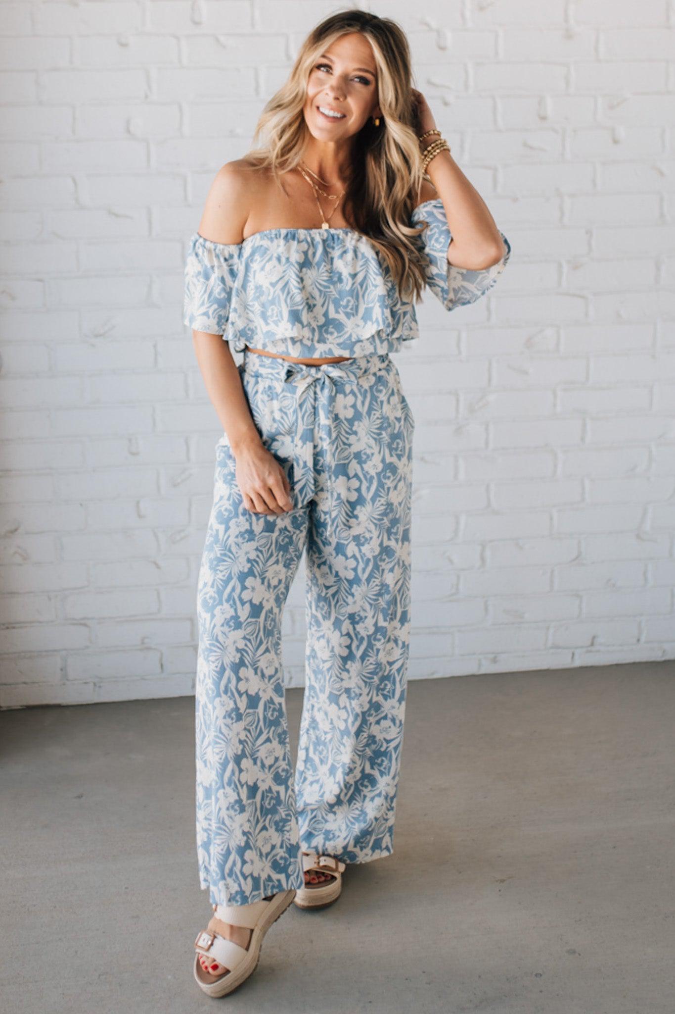 Blonde woman wearing blue and white floral wide leg pants with tie front and side pockets.