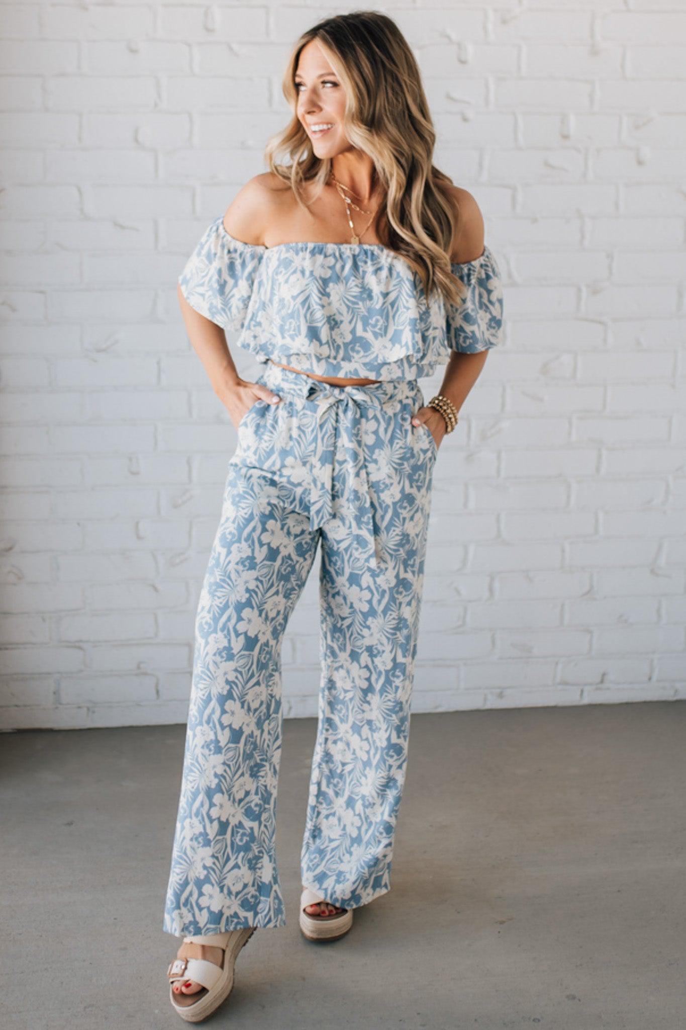 Blonde woman wearing blue and white floral wide leg pants with tie front and side pockets.