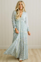 Woman wearing a long floral dress against a plain background