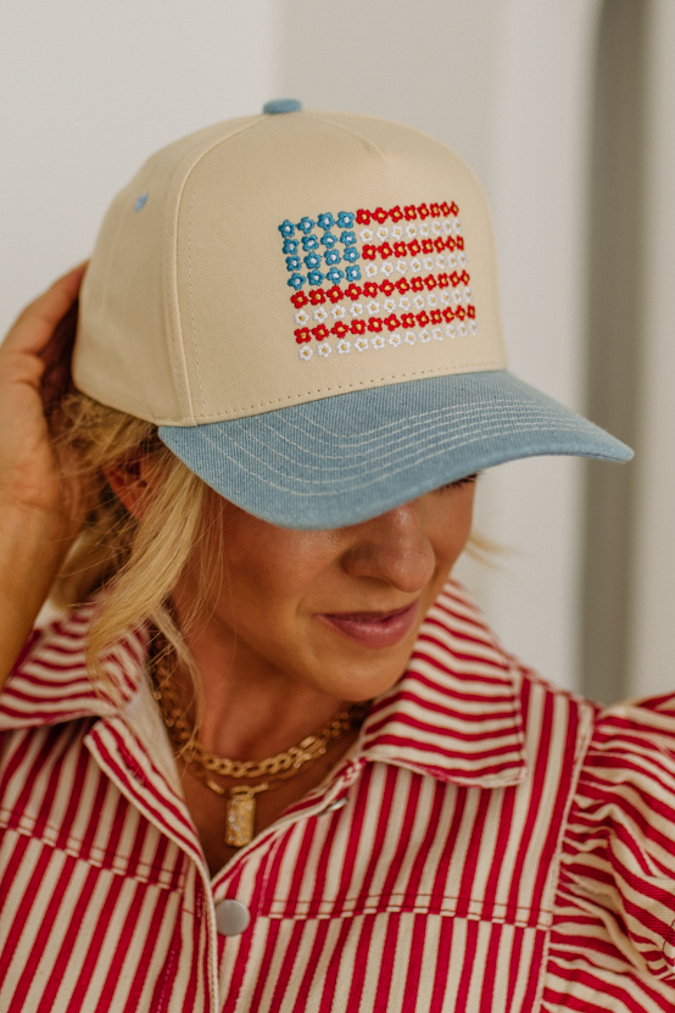 Person wearing a beige cap with a red, white, and blue pattern resembling an American flag.