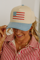 Person wearing a beige cap with a colorful design, smiling.