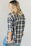 Woman wearing an oversized plaid top in navy, cream and brown tones.