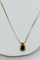 flat lay of black stone necklace with gold trim and gold chain