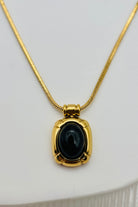 flat lay of black stone necklace with gold trim and gold chain