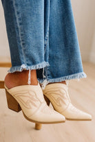 Finged jeans close up with cream embroidered western inspired slip on heel boots.