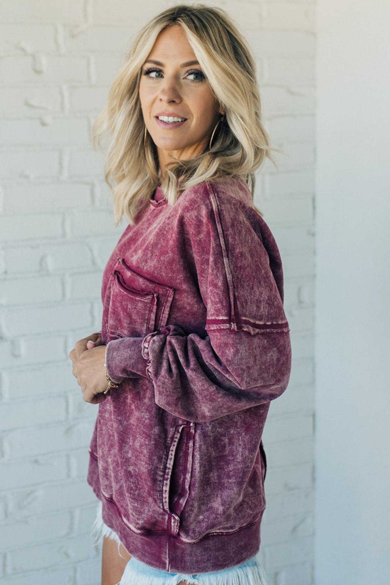 woman wearing a mineral washed wine colored pullover with ribbed details and exposed seams