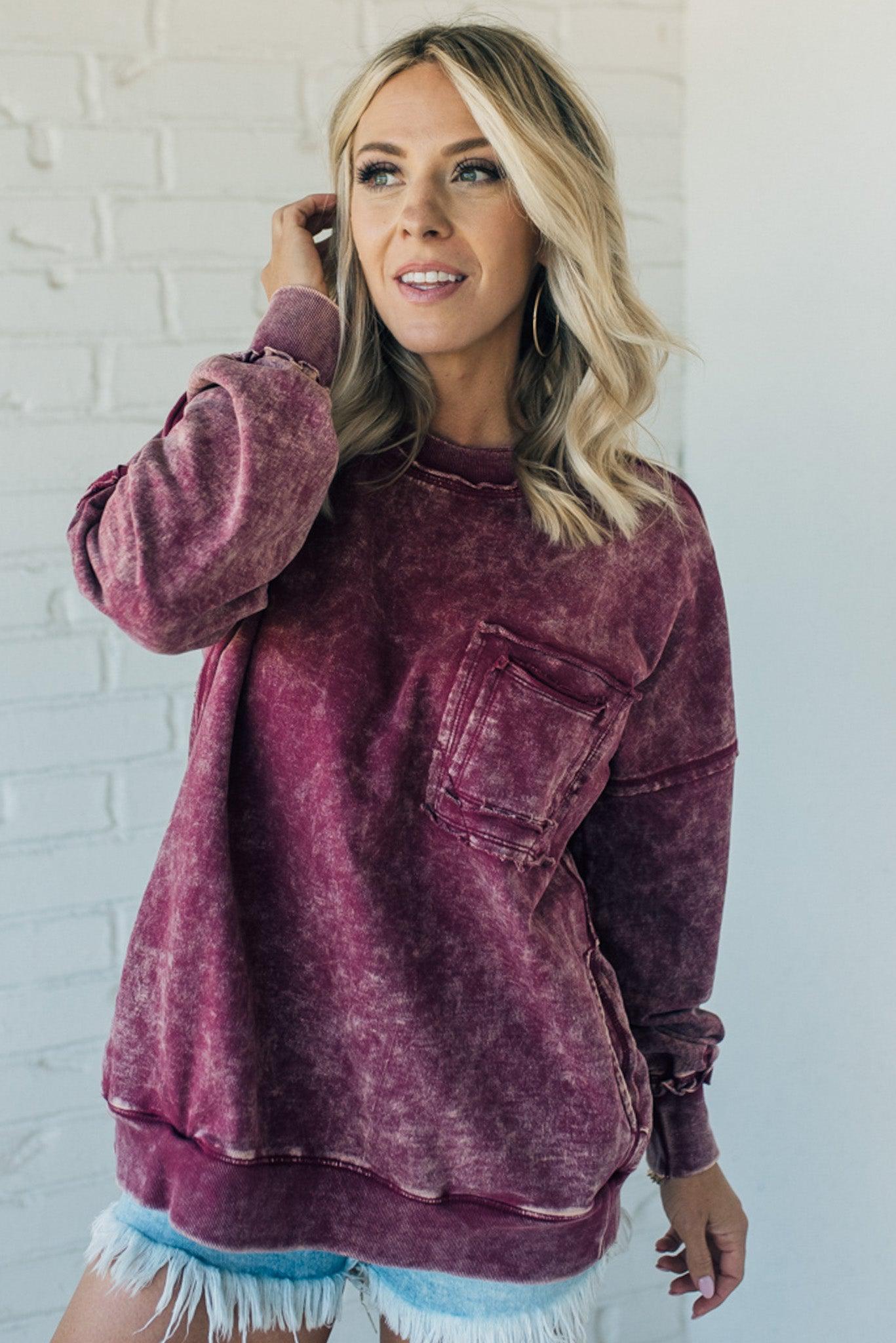 woman wearing a mineral washed wine colored pullover with ribbed details and exposed seams