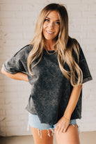 BLONDE WOMAN WEARING A FRENCH TERRY, ACID-WASHED TEE SHIRT WITH RAW EDGE ON NECKLINE AND A BOXY FIT.