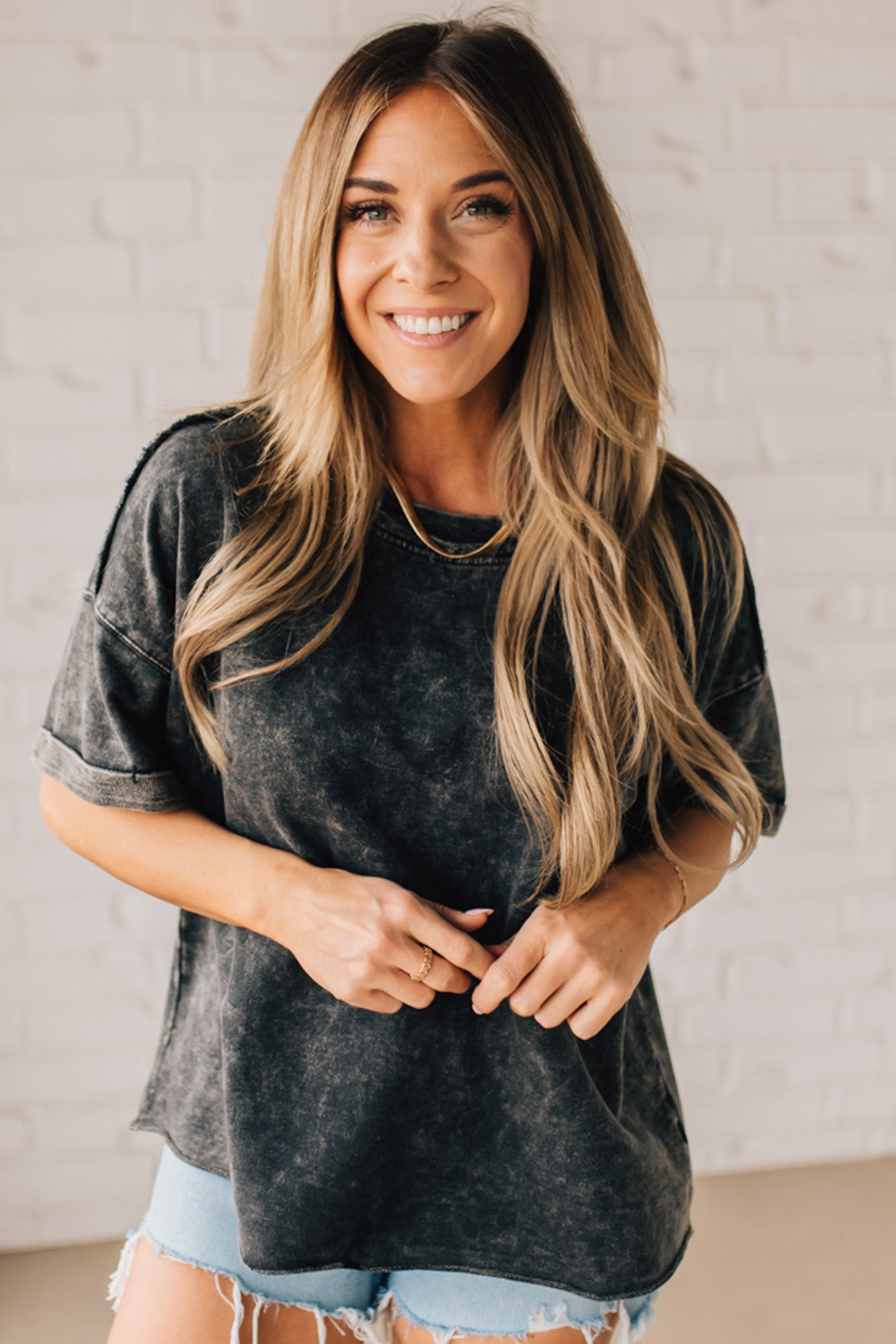 BLONDE WOMAN WEARING A FRENCH TERRY, ACID-WASHED TEE SHIRT WITH RAW EDGE ON NECKLINE AND A BOXY FIT.