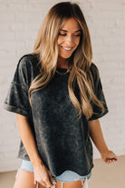 BLONDE WOMAN WEARING A FRENCH TERRY, ACID-WASHED TEE SHIRT WITH RAW EDGE ON NECKLINE AND A BOXY FIT.