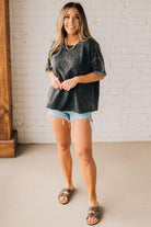 BLONDE WOMAN WEARING A FRENCH TERRY, ACID-WASHED TEE SHIRT WITH RAW EDGE ON NECKLINE AND A BOXY FIT.