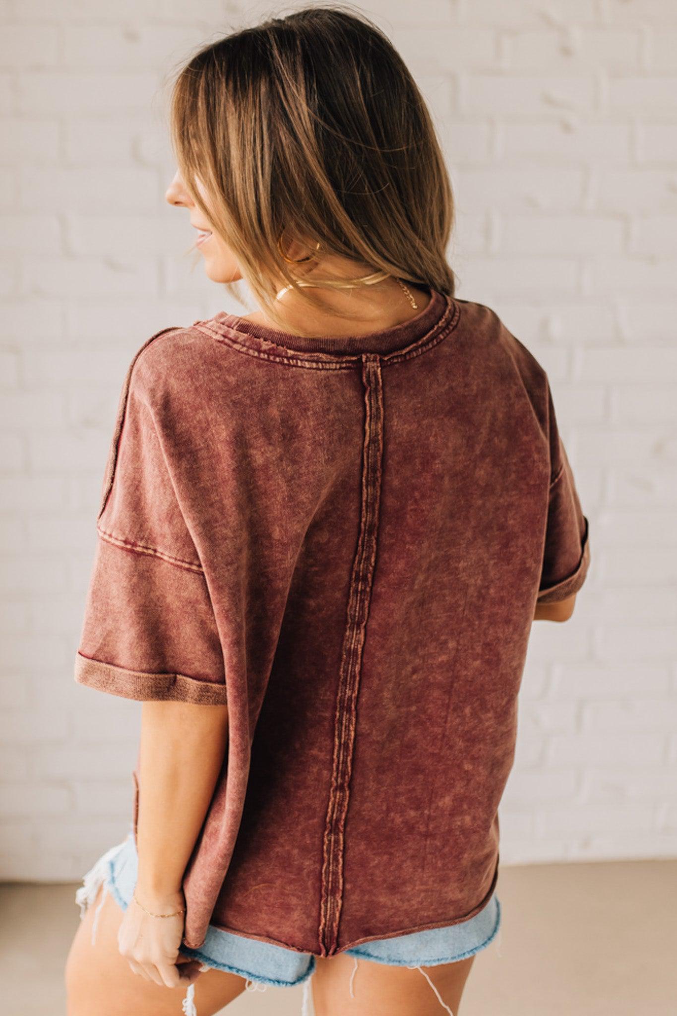 BLONDE WOMAN WEARING A FRENCH TERRY, ACID-WASHED TEE SHIRT WITH RAW EDGE ON NECKLINE AND A BOXY FIT.