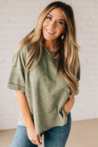 BLONDE WOMAN WEARING A FRENCH TERRY, ACID-WASHED TEE SHIRT WITH RAW EDGE ON NECKLINE AND A BOXY FIT.