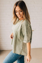 BLONDE WOMAN WEARING A FRENCH TERRY, ACID-WASHED TEE SHIRT WITH RAW EDGE ON NECKLINE AND A BOXY FIT.