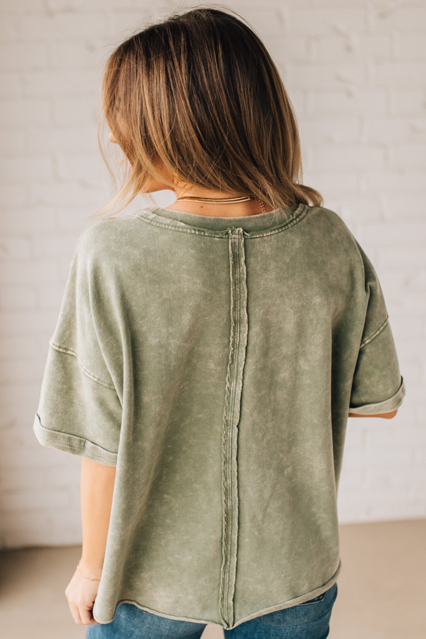 BLONDE WOMAN WEARING A FRENCH TERRY, ACID-WASHED TEE SHIRT WITH RAW EDGE ON NECKLINE AND A BOXY FIT.