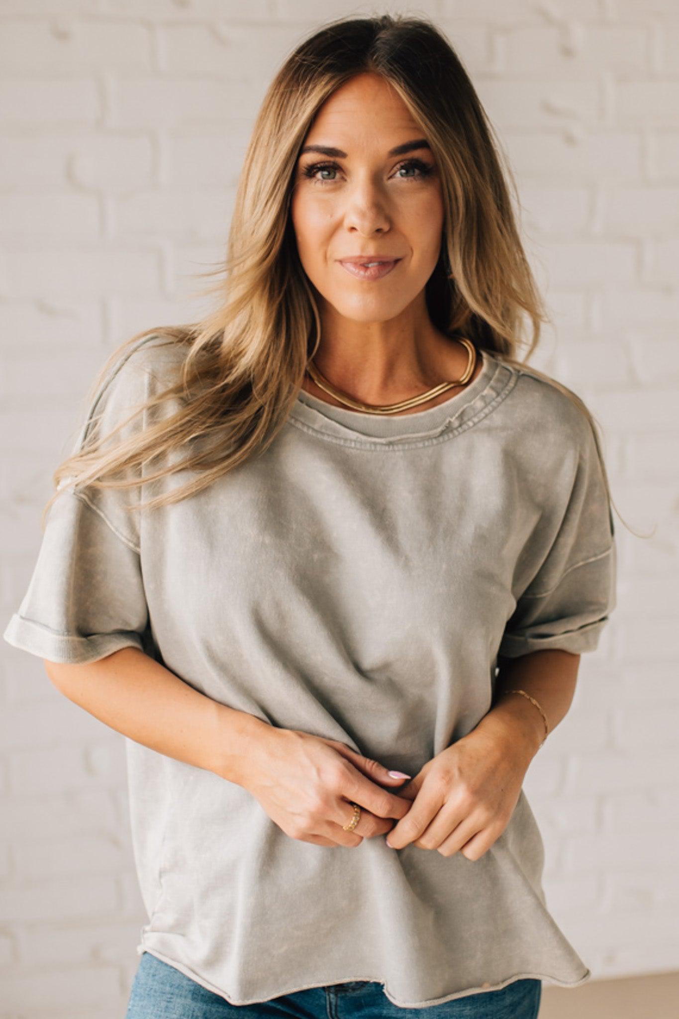 BLONDE WOMAN WEARING A FRENCH TERRY, ACID-WASHED TEE SHIRT WITH RAW EDGE ON NECKLINE AND A BOXY FIT.