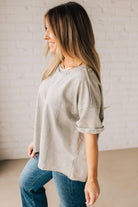 BLONDE WOMAN WEARING A FRENCH TERRY, ACID-WASHED TEE SHIRT WITH RAW EDGE ON NECKLINE AND A BOXY FIT.