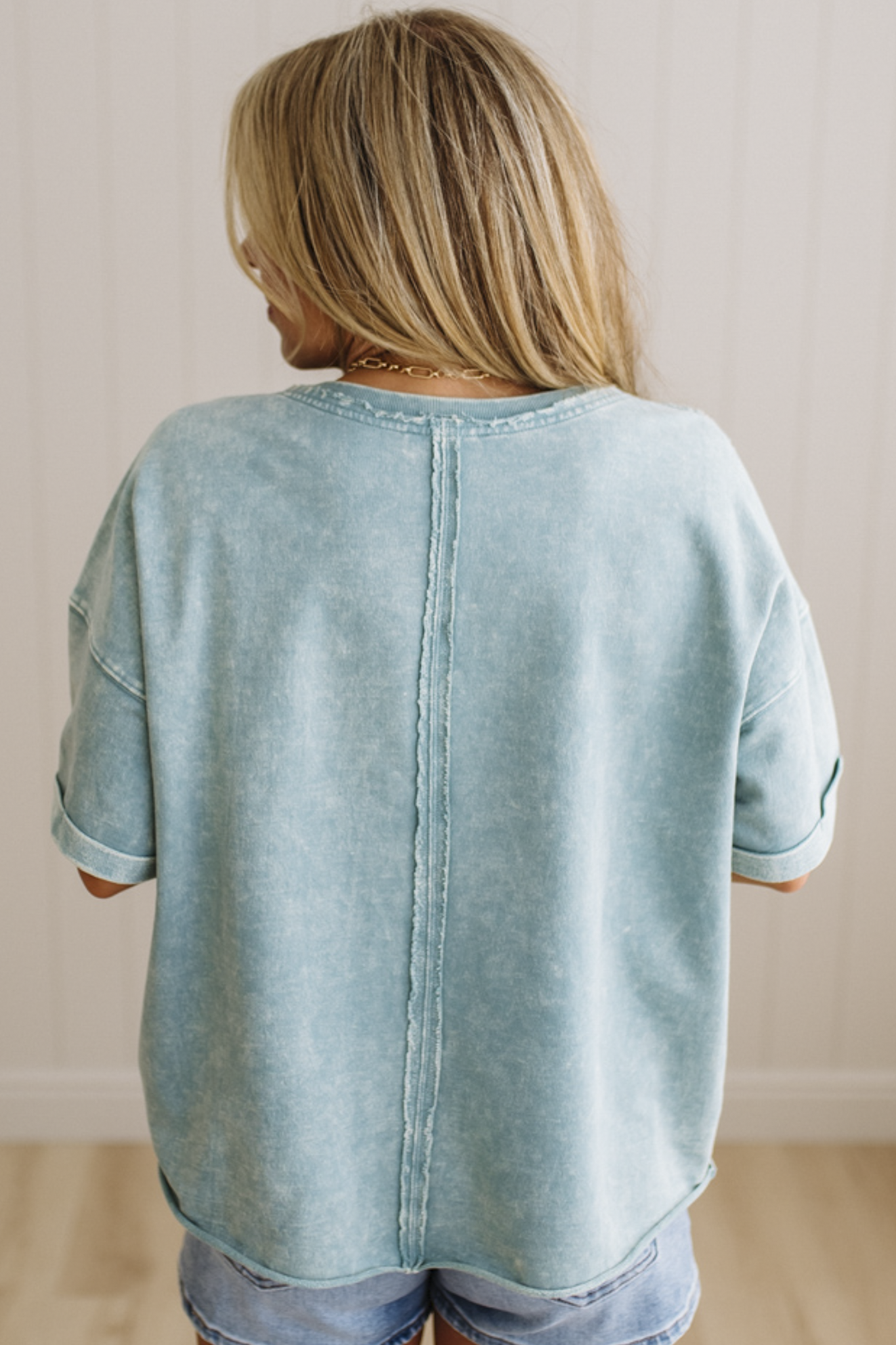Person wearing a light blue denim shirt with a neutral background