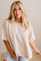 Woman wearing a beige oversized t-shirt and denim shorts against a plain background