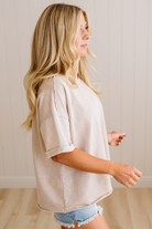 Woman wearing a beige oversized shirt and denim shorts in a neutral setting