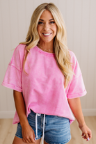 Woman wearing a pink oversized t-shirt and denim shorts indoors.