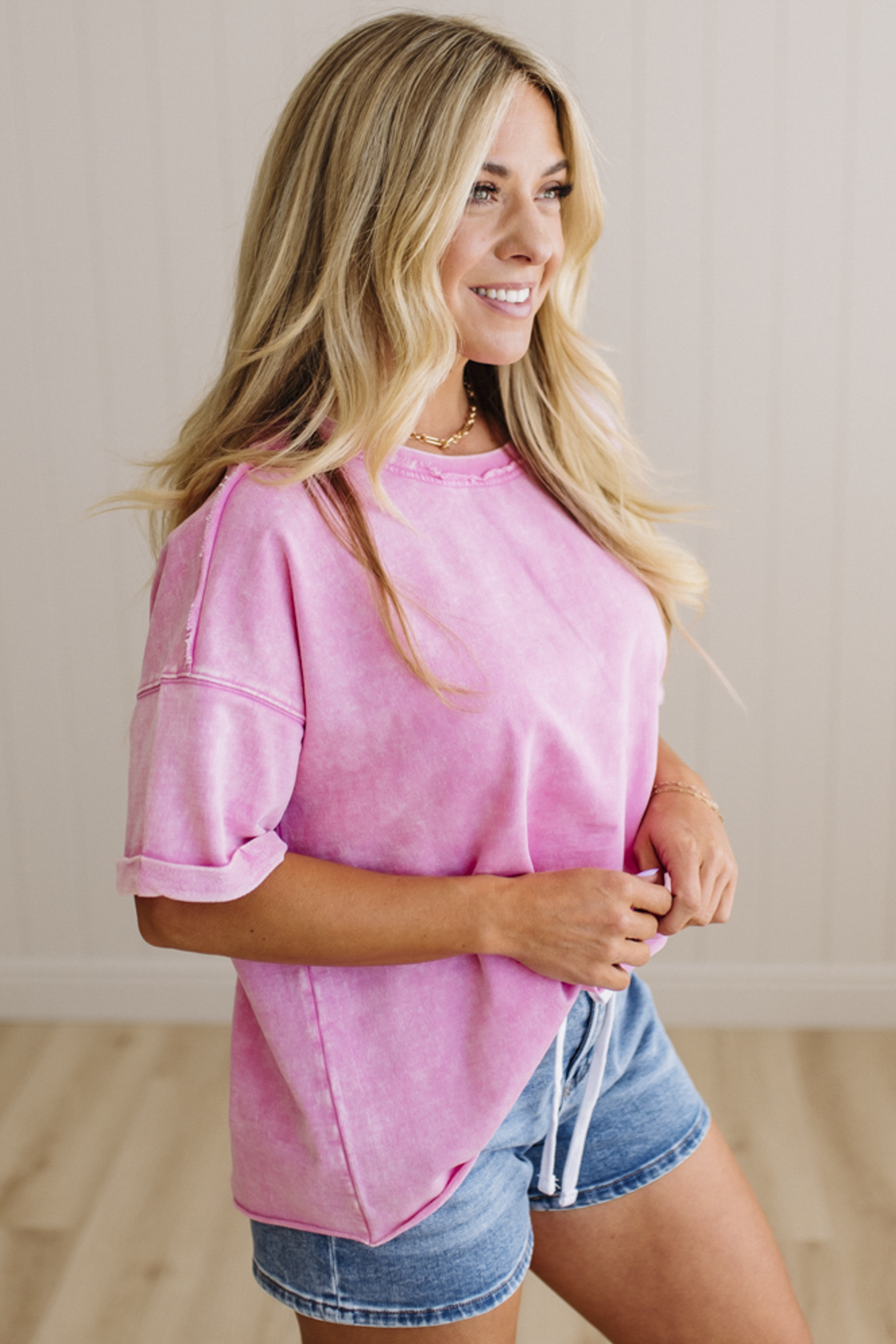 Woman wearing a pink top and denim shorts indoors