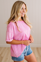 Woman wearing a pink top and denim shorts indoors