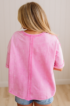 Person wearing a pink shirt and denim shorts against a plain background