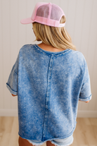 Person wearing a blue acid-wash shirt and pink cap from behind