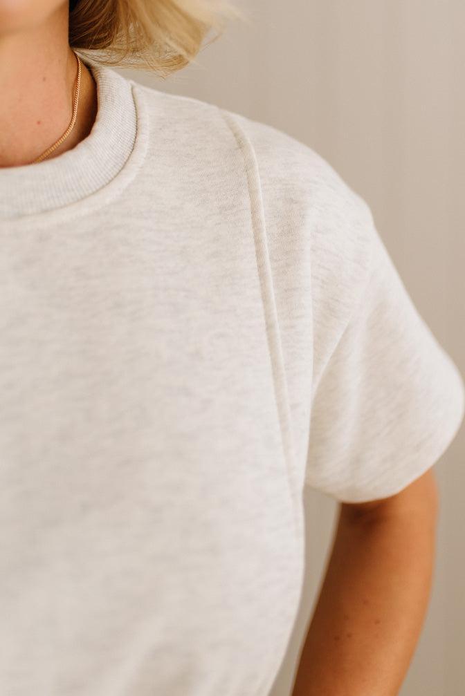 Close-up of a person wearing a plain white t-shirt against a neutral background
