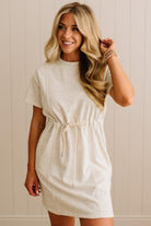 Woman wearing a beige dress against a neutral background