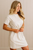 Woman wearing a white dress against a beige wall