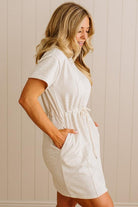 Woman wearing a white dress against a beige wall