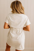 Person wearing a light-colored dress against a white paneled wall