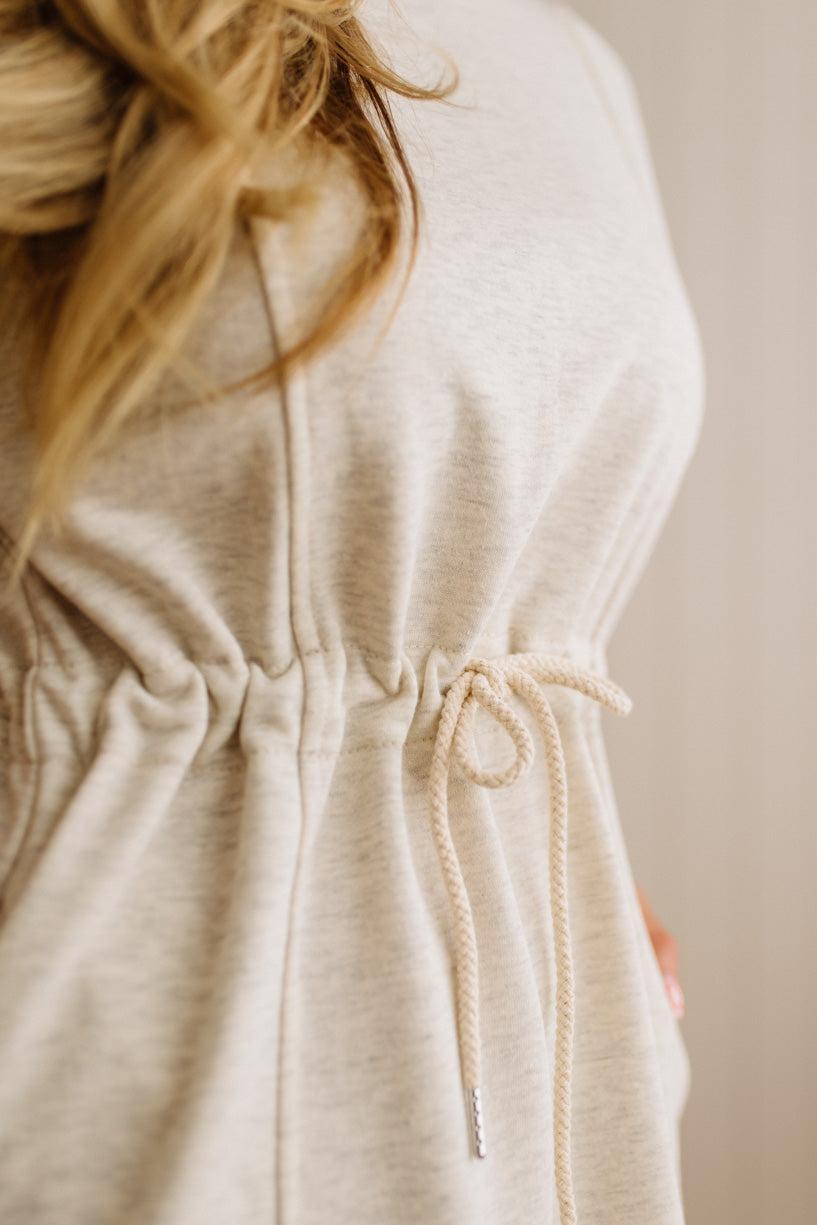 Close-up of a beige hoodie with a drawstring on a neutral background