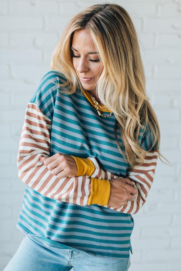 Woman wearing a striped sweater with yellow cuffs and a white background